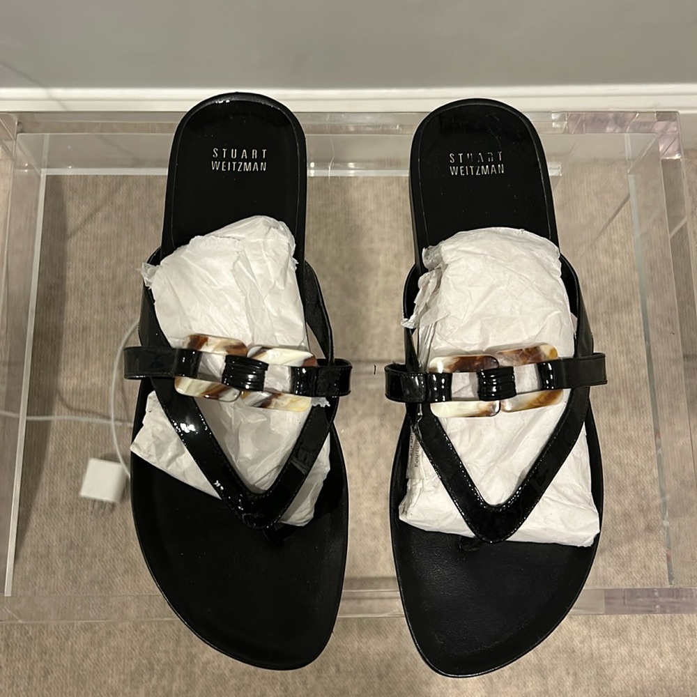 Stuart Weitzman, black patent leather sandals with tortoise buckle.